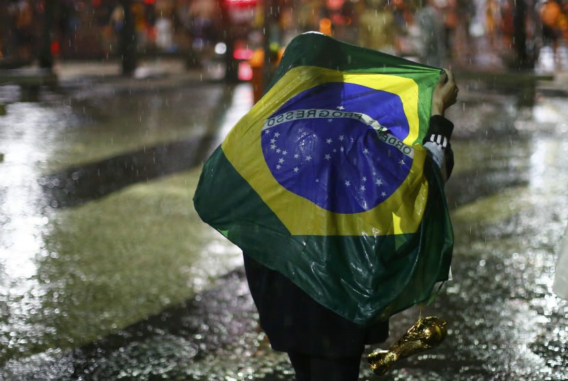 Seorang fan Brasil berjalan di bawah guyuran hujan setelah menonton Timnas Brasil menelan kekalahan 1-7 dari Jerman di semifinal Piala Dunia 2014 di Rio de Janeiro pada Selasa (8/7) 