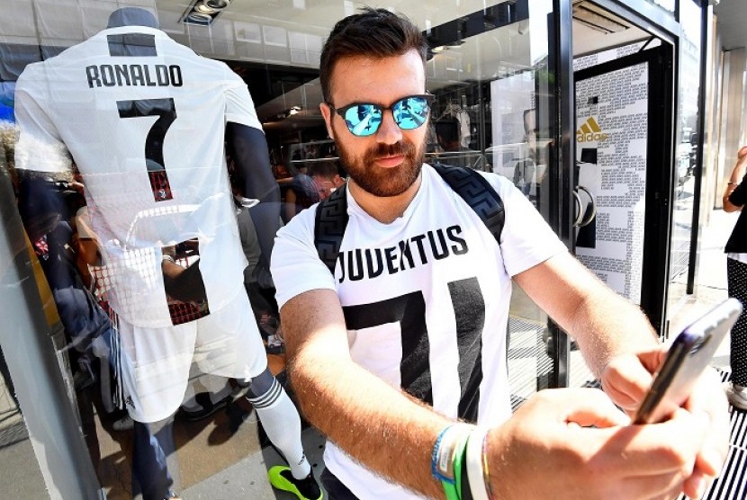 Seorang fan Juventus berfoto dengan kostum Cristiano Ronaldo di toko resmi Juventus di Milan.