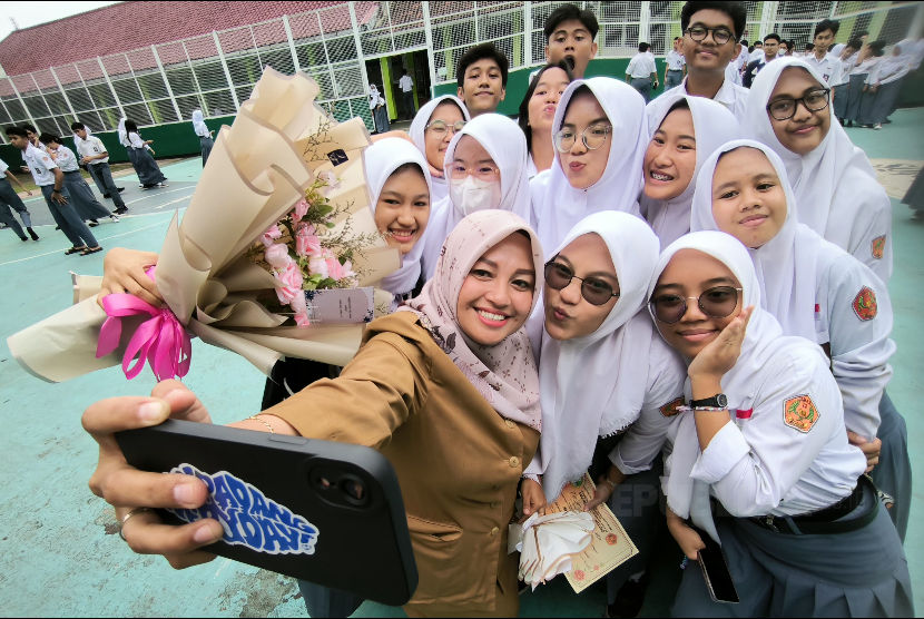 Seorang guru berswafoto bersama siswanya di sela peringatan Hari Guru Nasional di SMA Negeri 12 Bandung, Senin (27/11/2023). 