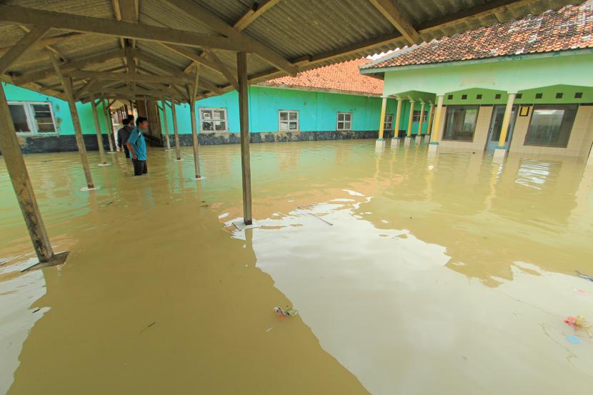 Seorang guru melihat banjir rob yang merendam bangunan SDN Eretan Wetan 1 di Kandanghaur, Indramayu, Jawa Barat, Rabu (13/1/2021). Banjir rob akibat pasang air laut itu merendam ratusan rumah warga, bangunan sekolah dan mushola di kecamatan itu.