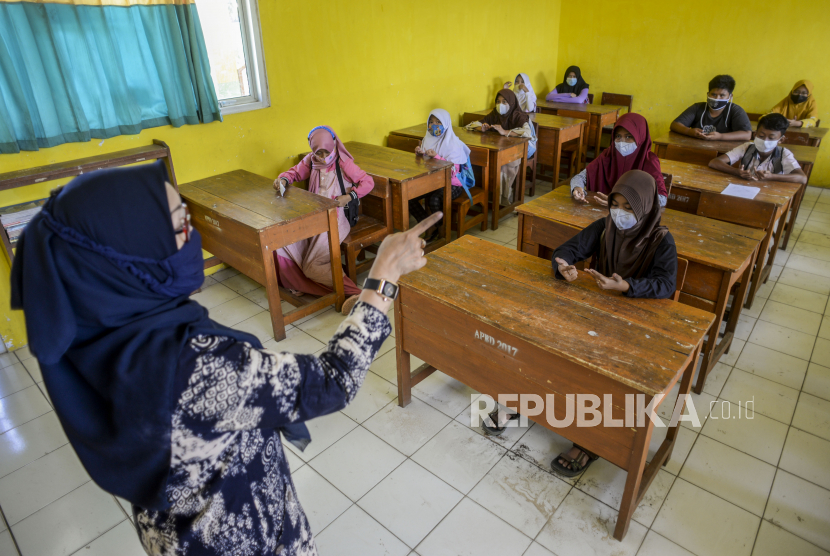 Seorang guru memberikan penjelasan kepada anak-anak saat uji coba pembelajaran tatap muka (PTM) di SDN Cihideung Ilir 5, Ciampea, Kabupaten Bogor, Jawa Barat, Rabu (25/8). Uji coba itu sebagai fase adaptasi bagi para pelajar menjelang diselenggarakannya PTM pada Senin (30/8) di sekolah tersebut. Pemerintah Kabupaten Bogor sudah memperbolehkan diselenggarakannya PTM pada Rabu (25/8) pasca penurunan status PPKM dari level 4 ke 3. Republika/Putra M. Akbar