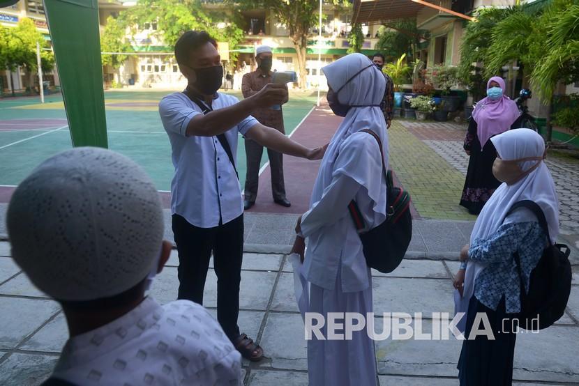 Seorang guru memeriksa suhu badan calon murid yang akan mengikuti ujian berbasis komputer dan tes kemampuan membaca Al Quran di Madrasah Tsanawiyah Negeri (MTsN) di Banda Aceh, Aceh, Rabu (10/6). (ilustrasi)