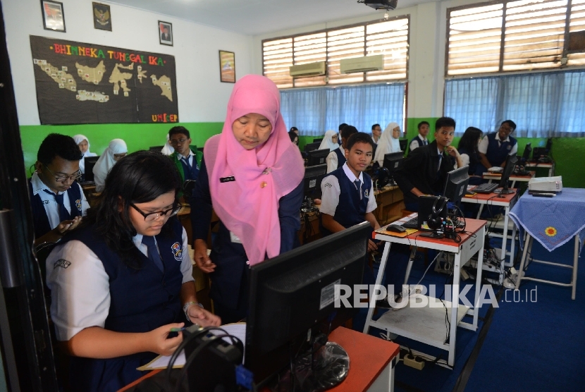Seorang guru mengarahkan muridnya sesaat sebelum melakukan Ujian Nasional Berbasis Komputer (UNBK) di SMP Negeri 30, Jakarta Utara, Senin (9/5