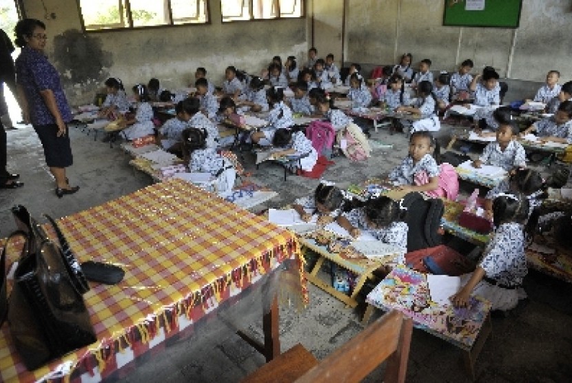 Seorang guru mengawasi siswa kelas 2 belajar di lantai di Sekolah Dasar Negeri 3 Sesetan Denpasar, Bali, Kamis (2/10).