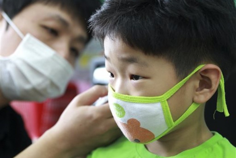 Seorang guru mengenakan masker kepada muridnya  untuk mengantisipasi wabah MERS di Seoul, Korea Selatan.