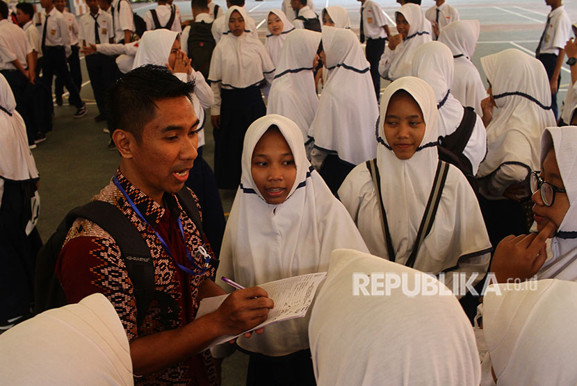 Seorang guru mengumpulkan siswa peserta Ujian Nasional Berbasis Kompetensi (UNBK) - SMP saat terjadi gangguan server di lapangan di SMP 12, Malang, Jawa Timur, Senin (23/4). 