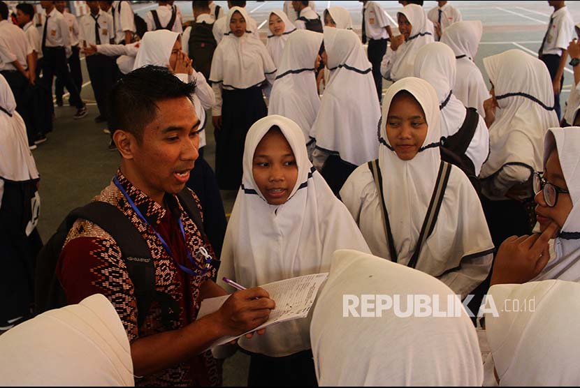Seorang guru mengumpulkan siswa peserta Ujian Nasional Berbasis Kompetensi (UNBK) - SMP saat terjadi gangguan server di lapangan di SMP 12, Malang, Jawa Timur, Senin (23/4). Akibat gangguan tersebut pelaksanaan UNBK sempat mundur selama 1,5 jam. 