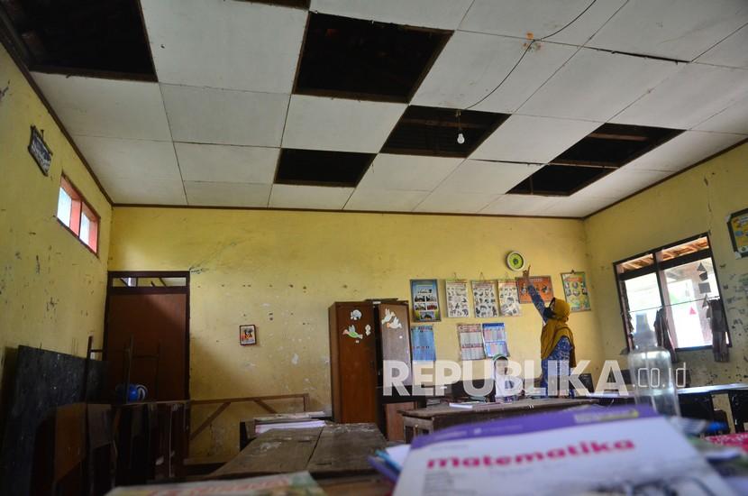 Seorang guru menunjukkan ruangan kelas yang plafonnya rusak  (ilustrasi)