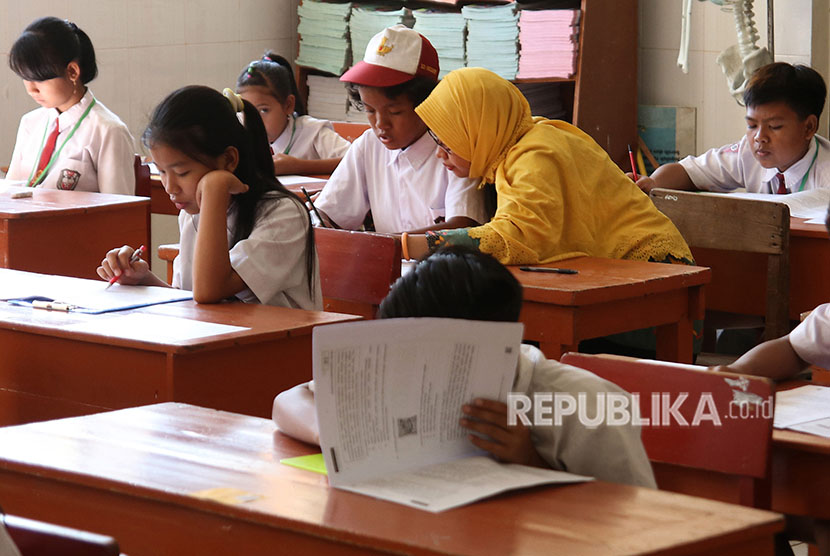 Seorang guru pedamping membacakan soal Ujian Sekolah Berstandar Nasional (USBN) kepada muridnya.