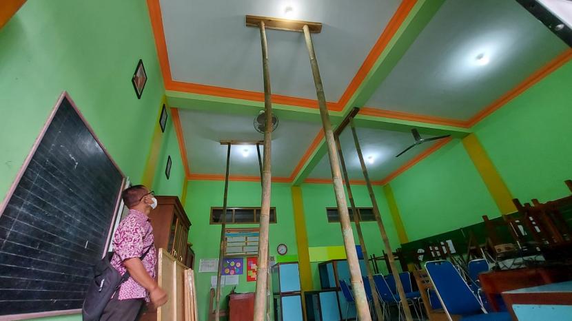 Seorang guru SDN Kupang 01, Kecamatan Ambarawa, Kabupaten Semarang, menunjukkan bagian kerusakan atap yang harus disangga dengan pilar- pilar bamboo agar tidak membahayakan KBM di sekolah, Selasa (2/11). Tiga ruang kelas di sekolah ini terdampak gempa tektonik yang terjadi di Ambarawa dan sekitarnya.