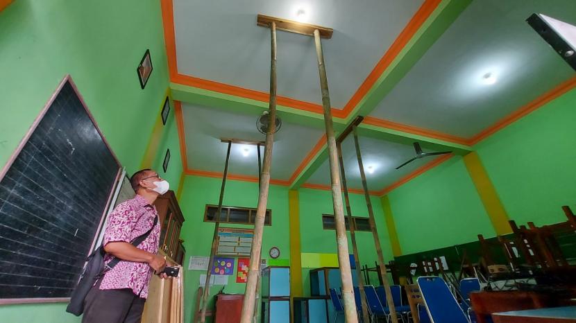 Seorang guru menunjukkan bagian kerusakan atap sekolah yang harus disangga dengan pilar- pilar bambu agar tidak membahayakan siswa (ilustrasi)