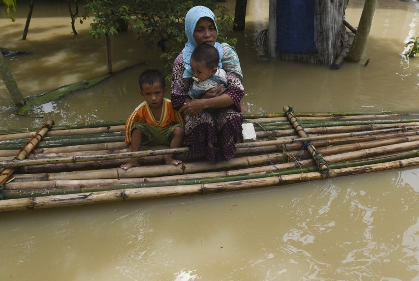 Seorang ibu bersama anaknya berada di atas rakit saat melintasi banjir di Baureno, Bojonegoro, Jawa Timur, Jumat (2/12).