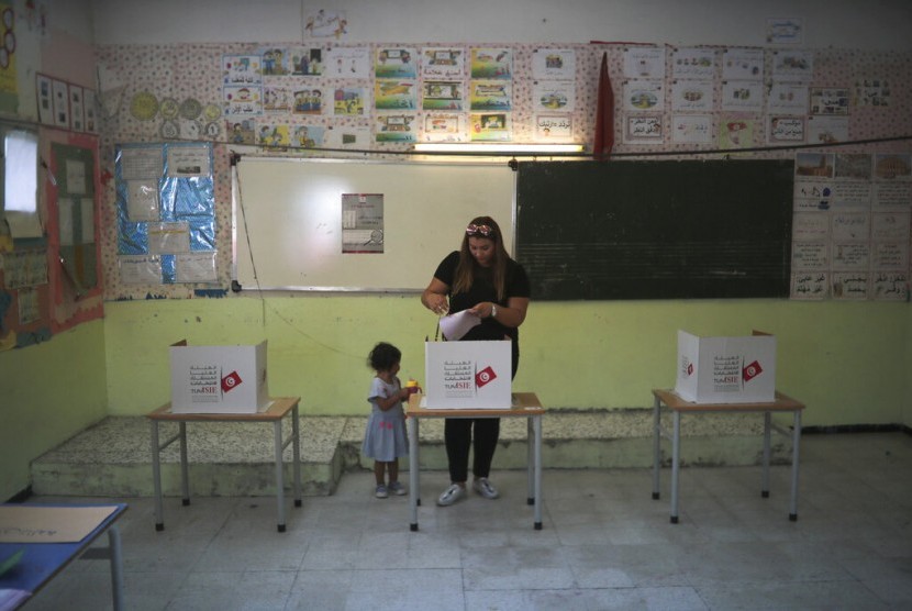 Seorang ibu dengan ditemani anaknya memberikan suara dalam pemilihan umum putaran pertama di Tunis, Tunisia, Ahad (15/9). 