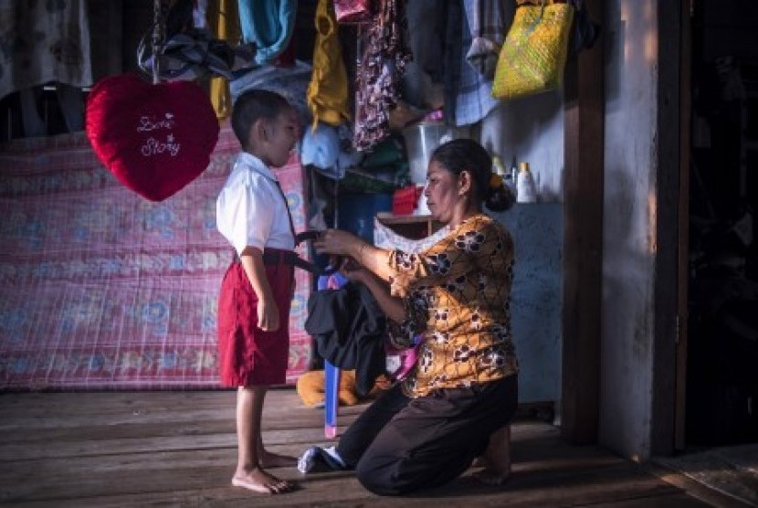 Seorang ibu di daerah terpencil di Kepulauan Karimata, Kalbar memakaikan seragam, Senin (19/10)