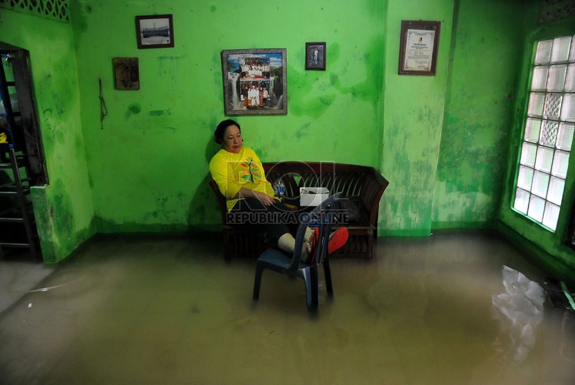    Seorang ibu duduk di dalam rumahnya yang terendam banjir di kawasan pemukiman Kampung Melayu Besar, Jakarta, Rabu (29/1).   (Republika/Prayogi)