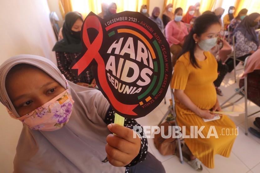 Seorang ibu hamil memperlihatkan kipas bertuliskan Hari AIDS Se-Dunia.
