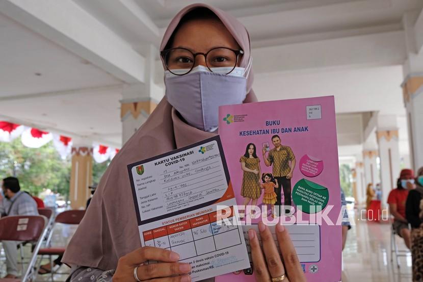 Seorang ibu hamil menunjukkan surat vaksin dan buku kesehatan ibu dan anak saat vaksinasi Covid-19 bagi ibu hamil di Lapangan DR Soepardi Sawitan, Mungkid, Magelang, Jawa Tengah, Senin (30/8/2021).