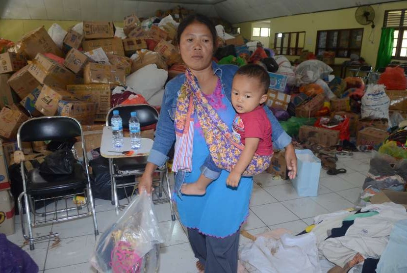 Seorang ibu korban gempa dan tsunami Palu-Donggala mengambil barang kebutuhannya dari donasi masyarakat saat tiba di Asrama Haji Sudiang, Makassar, Sulawesi Selatan, Rabu (3/10).