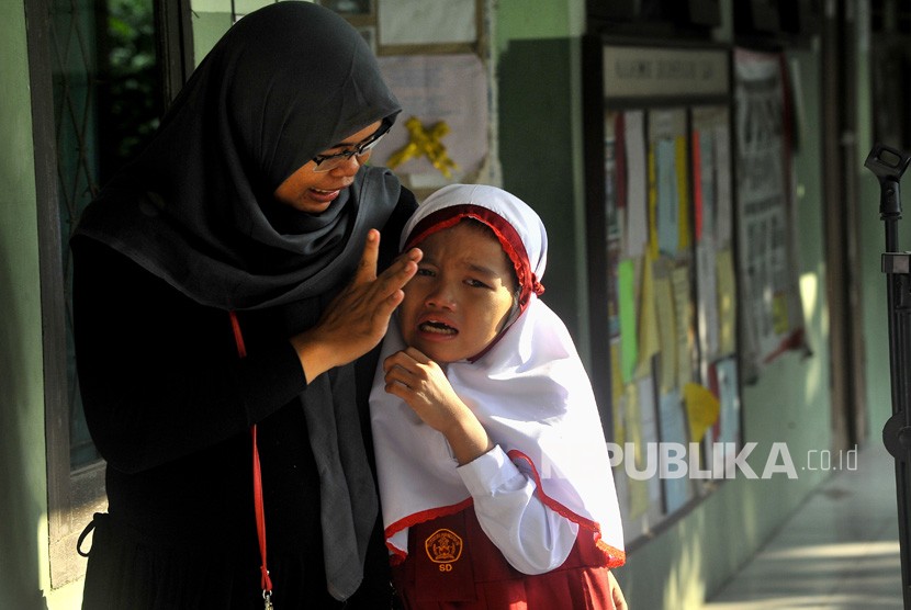 Seorang ibu menenangkan anaknya yang menangis saat hari pertama masuk sekolah di SD Negeri Sumber Agung, di Jalan Bayangkara, Serang, Banten, Senin (16/7).