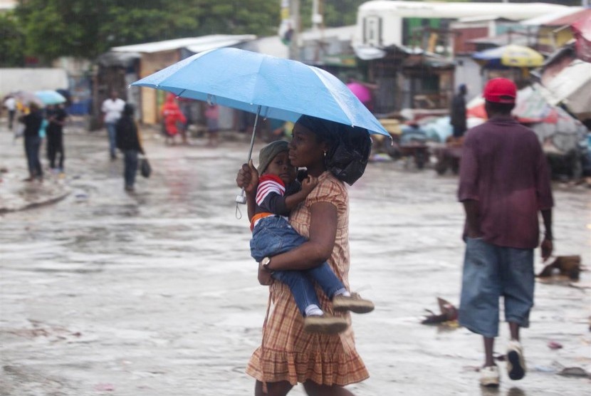 Seorang ibu menggendong anaknya di tengah hujan akibat Topan Matthew di Port-au-Prince, Haiti.