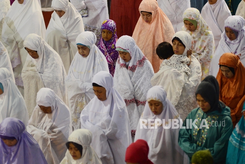 Seorang ibu menggendong anaknya saat melaksanakan Shalat Idul Adha di Masjid Istiqlal, Jakarta.