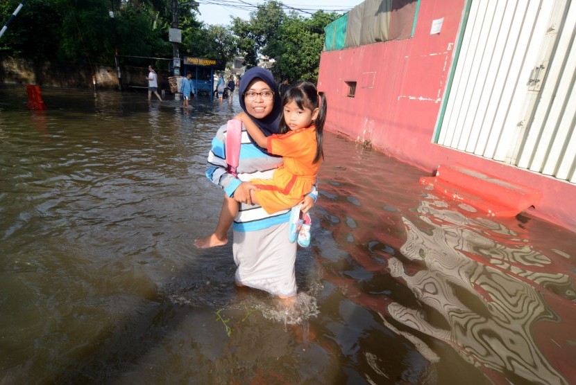 Seorang ibu menggendong anaknya yang akan berangkat ke sekolah menembus banjir di Perumahan Ciledug Indah 1, Tangerang, Banten, Rabu (22/2). Luapan Kali Angke menyebabkan ratusan rumah di kawasan perumahan tersebut terendam banjir hingga setinggi 60 cm. 