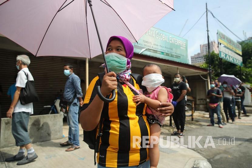Malaysia Minta Perayaan Idul Fitri tak Lebih dari 20 Orang. Seorang ibu menggendong putrinya mengenakan masker usai menjalani tes COVID-19 di pasar Raja Bot di Kampong Bharu di Kuala Lumpur, Malaysia