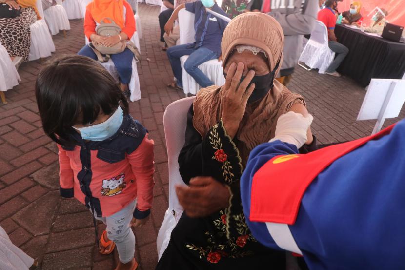 Seorang ibu menutup mata saat mendapatkan suntikan vaksin COVID-19 di kawasan monumen Simpang Lima Gumul, Kediri, Jawa Timur, Kamis (10/6/2021). Pemberian vaksin massal untuk masyarakat umum di atas umur 18 tahun tersebut guna mendongkrak serapan vaksinasi COVID-19.