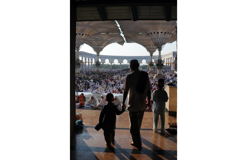 Seorang jamaah bersama anaknya keluar dari masjid usai melaksanakan shalat Ied di Masjid Agung Jawa Tengah (MAJT), Semarang, Ahad (19/8). (Aditya Pradana Putra/Republika)