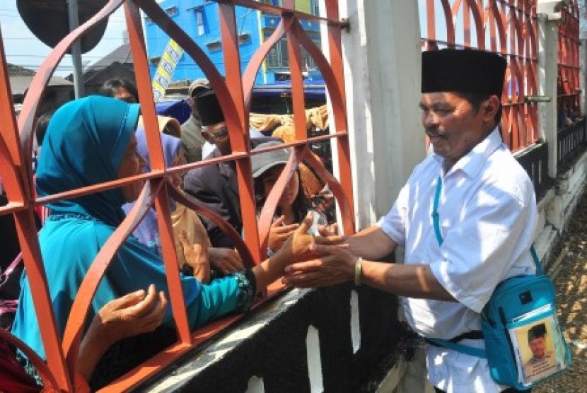 Seorang jamaah calon haji menyalami keluarga dari balik pagar Embarkasi Haji Adisumarmo, Donohudan, Boyolali, Jawa Tengah, Minggu (23/8).
