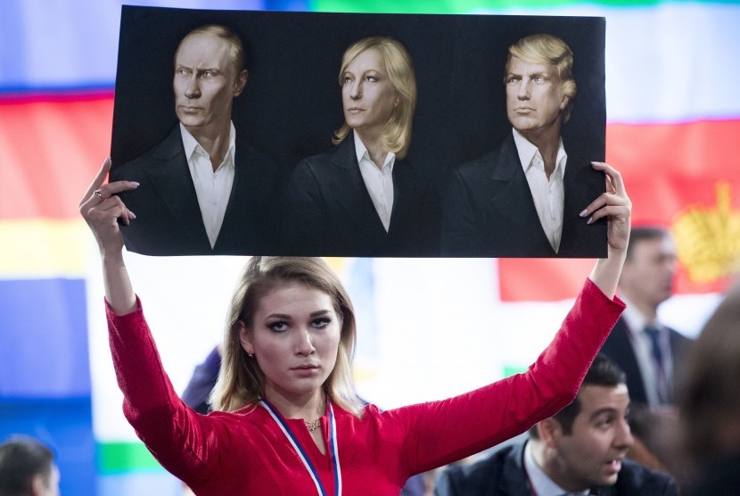 Seorang jurnalis memegang poster bergambar presiden Rusia, Vladimir Putin (kiri), Presiden Front Nasional sayap kanan Prancis, Marine Le Pen (tengah), dan Presiden terpilih AS, Donald Trump (kanan)