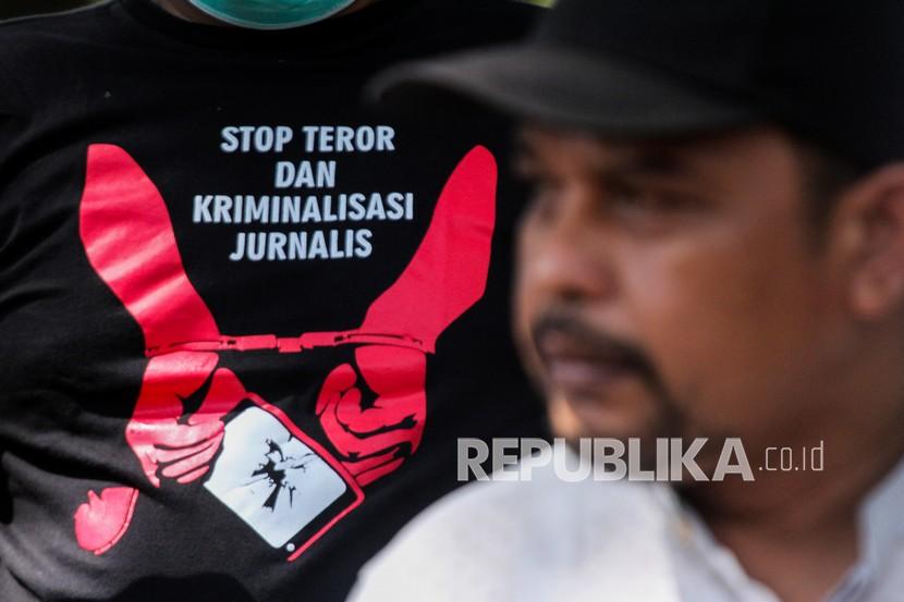 Seorang jurnalis mengenakan kaos bertuliskan 'stop teror dan kriminalisasi jurnalis'.