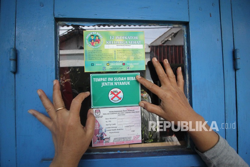 Seorang kader Ibu Memantau Jentik (Bumantik) menempelkan stiker bebas jentik nyamuk di salah satu rumah warga saat Gerakan Pemberantasan Sarang Nyamuk. Ilustrasi