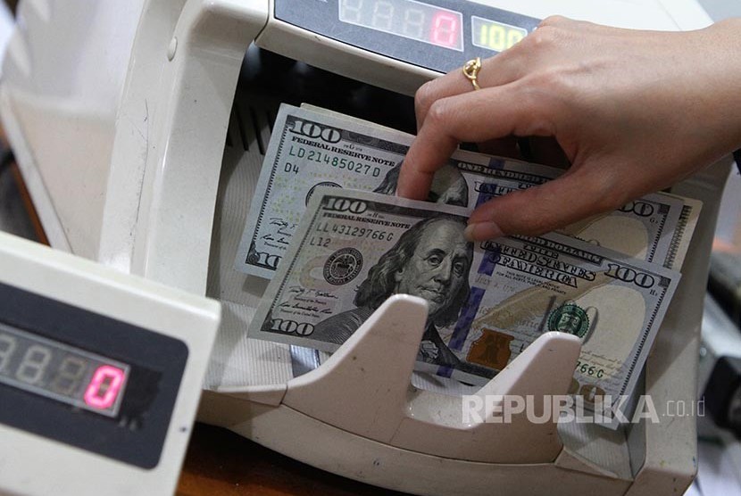 Ilustrasi seorang karyawan melayani penukaran uang dolar AS di sebuah gerai Kegiatan Usaha Penukaran Valuta Asing Bukan Bank (KUPVA BB). 