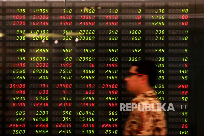 Seorang karyawan melintas di depan monitor pergerakan Indeks Harga Saham Gabungan (IHSG) di Plaza Mandiri, Jakarta, Senin (29/1). Indeks Harga Saham Gabungan (IHSG) pada perdagangan hari ini ditutup menguat 20 poin atau 0,3 persen dibanding penutupan kemarin. IHSG pun kembali mencetak rekor baru di level 6.680, kendati investor asing mencatatkan jual bersih pada perdagangan hari ini.