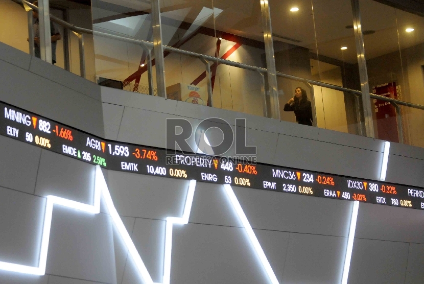 Seorang karyawan melintas didekat layar elektronik pergerakan Indeks harga saham gabungan (IHSG) di gedung Bursa Efek Indonesia, Jakarta.