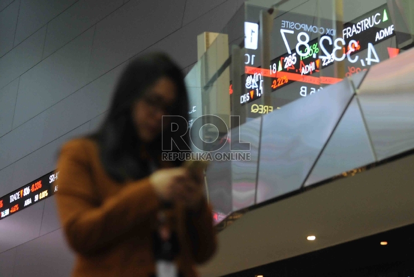 Seorang karyawan melintas didekat layar elektronik pergerakan Indeks harga saham gabungan (IHSG) di gedung Bursa Efek Indonesia, Jakarta, Jumat (11/9).