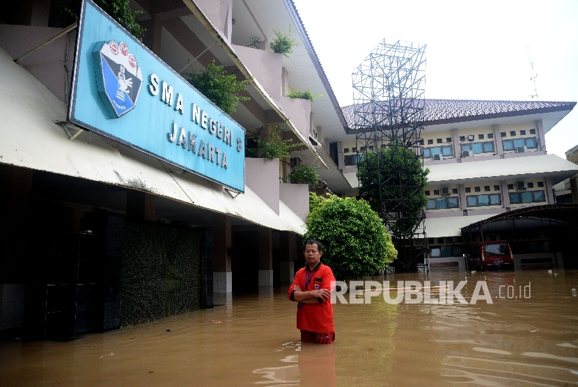  Seorang karyawan melintasi banjir yang menggenagi halaman sekolah SMA Negeri 8 , Bukit Duri, Jakarta, Kamis (16/2). 