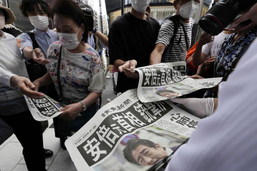  Seorang karyawan membagikan edisi tambahan surat kabar Yomiuri Shimbun yang melaporkan mantan perdana menteri Jepang Shinzo Abe ditembak, Jumat, 8 Juli 2022, di Tokyo. Kampanye di Jepang pada hari terakhir sebelum pemilu tetap berlanjut usai Abe wafat.
