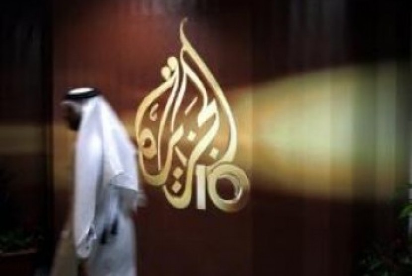Seorang karyawan stasiun televisi Arab Al Jazeera berjalan melewati logo Al Jazeera di Doha, Qatar.