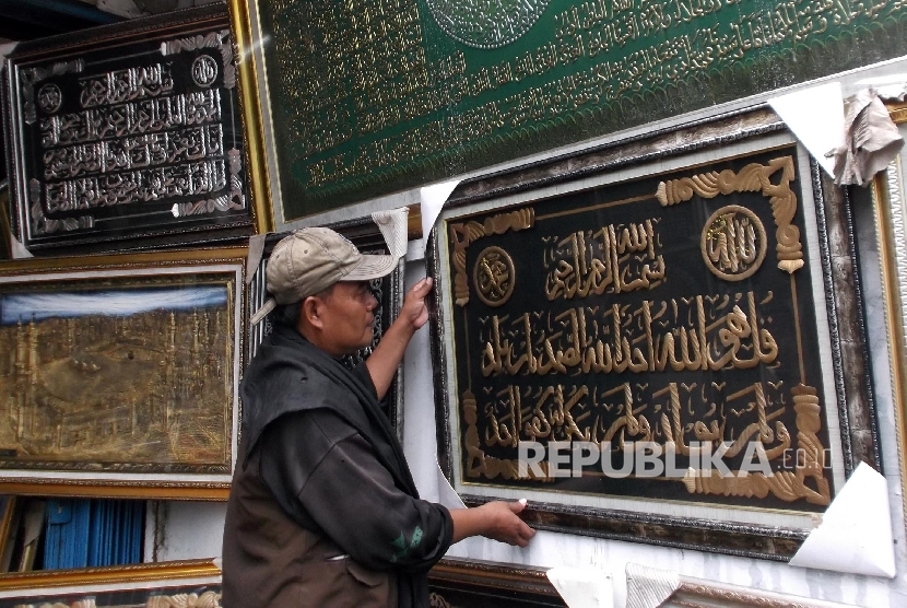 Seorang karyawan toko frame merapihkan display kaligrafi di tokonya di Jakarta, Senin (21/3). 