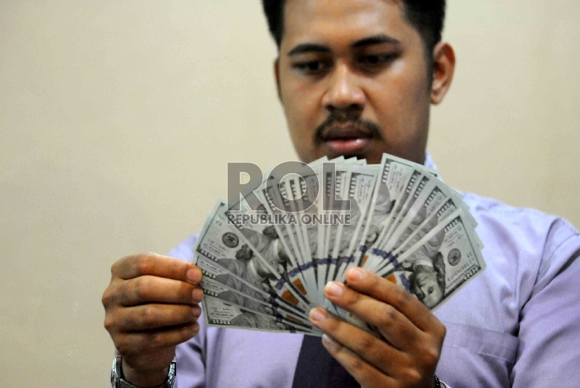  Seorang karyawan toko penukaran valuta asing menghitung uang dolar AS di tempat penukaran uang di Sarinah, Jakarta, Senin (21/9). (Republika/Agung Supriyanto)