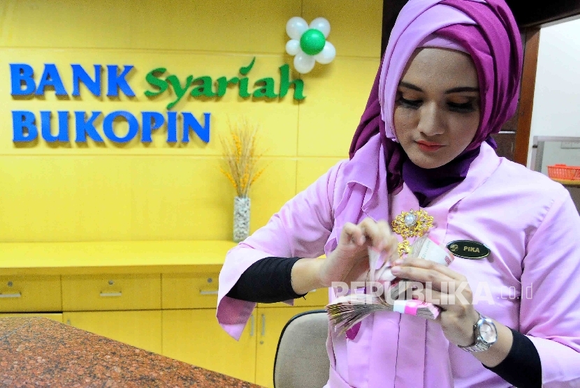 Seorang karyawati tengah menghitung uang di Banking Hall Bank Syariah Bukopin, Jakarta. ilustrasi 