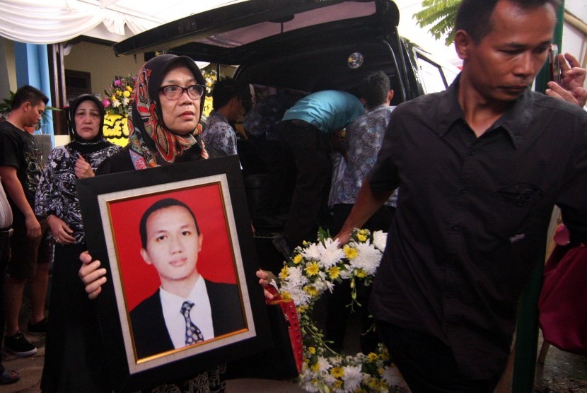 Seorang kerabat membawa foto dokter Dionisius Giri Samodra alias dr Andra (24) saat jenazah tiba di rumah duka di Komplek Mahkamah Agung, Pamulang, Tangerang Selatan, Banten, Jumat (13/11).  (Antara/Muhammad Iqbal)