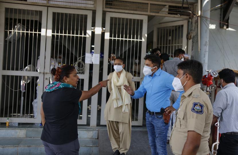 Seorang kerabat pasien berdebat dengan petugas polisi di luar rumah sakit pemerintah COVID-19 di Ahmedabad, India, Selasa, 27 April 2021. Kasus virus corona di India melonjak lebih cepat daripada di tempat lain di dunia.