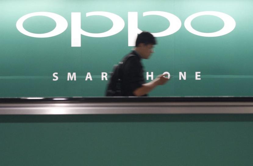 Seorang komuter menggunakan ponselnya melewati iklan pembuat smartphone China Oppo di sebuah stasiun kereta api di Singapura 8 Mei 2014. Foto ilustrasi.