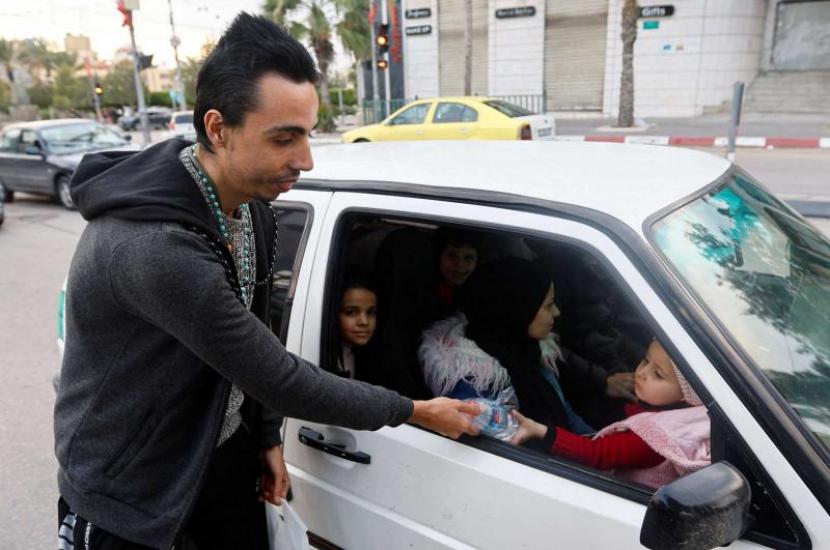 Seorang Kristen Palestina Ehab Ayyad menawarkan kurma dan air kepada umat Islam yang terjebak kemacetan atau terlambat pulang untuk berbuka puasa selama Ramadhan, di Kota Gaza, Kamis (13/4/2023). Pria Kristen Gaza Jadi Contoh Toleransi Langka Selama Ramadhan