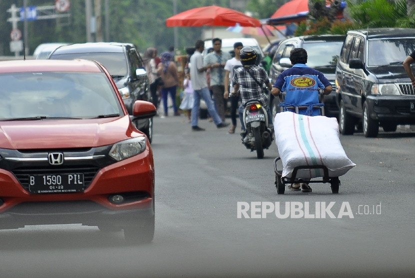 Seorang kuli angkut membawa barang bawaannya melintas di Pasar Tanah Abang, Jakarta Pusat, Senin (10/7).