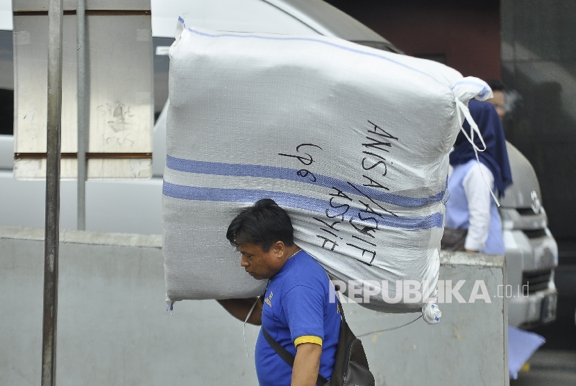 Seorang kuli panggul membawa barang bawaannya melintas di Pasar Tanah Abang, Jakarta Pusat, Senin (10/7). 