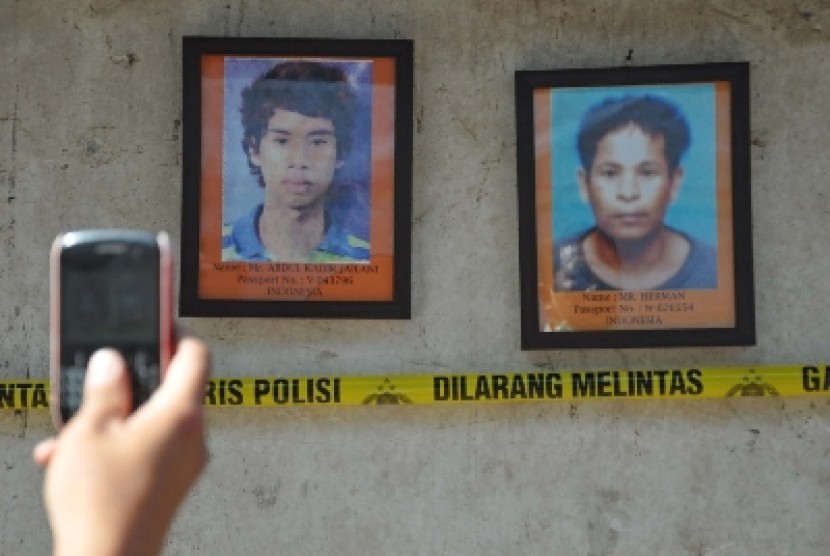 Seorang laki-laki mengambil gambar 2 foto TKI meninggal yang dipajang di lokasi otopsi di pemakaman keluarga Dusun Pancor Kopong, Desa Pringgesela, Kecamatan Pringgesela, Selong, Lombok Timur, NTB, Kamis (26/4). 